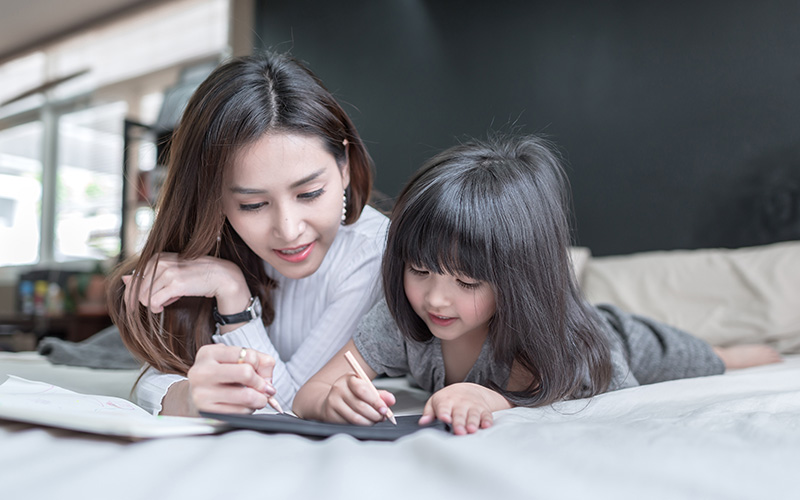 Mother guiding child in writing to build good English skills.
