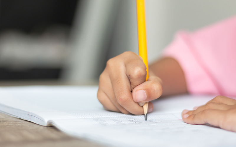 Primary student practicing writing for PSLE exam preparation.