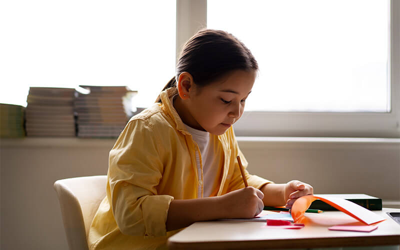 young-girl-writing-at-desk-near-window